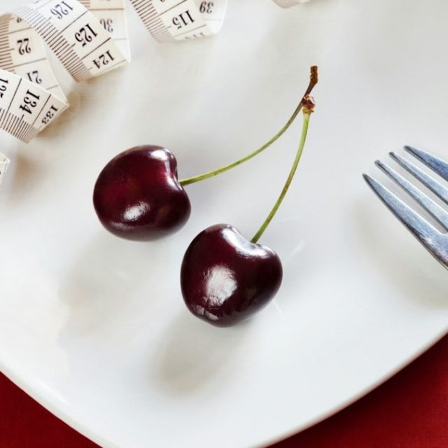 Diet white plate with centimeter, cherry, fork