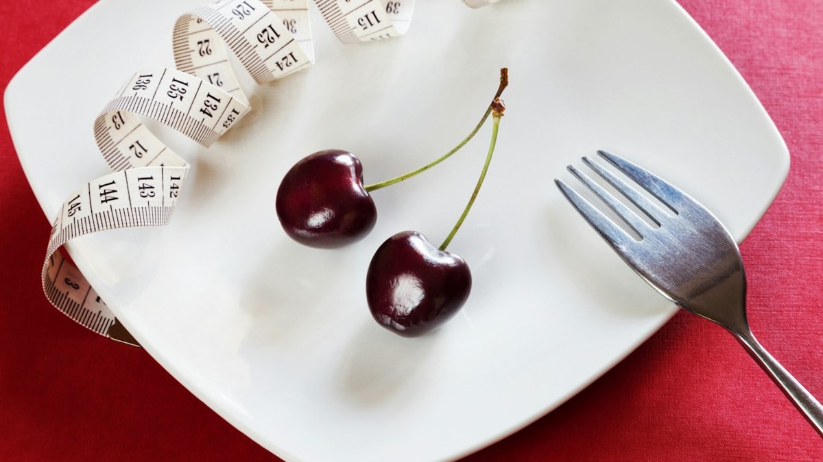 Diet white plate with centimeter, cherry, fork